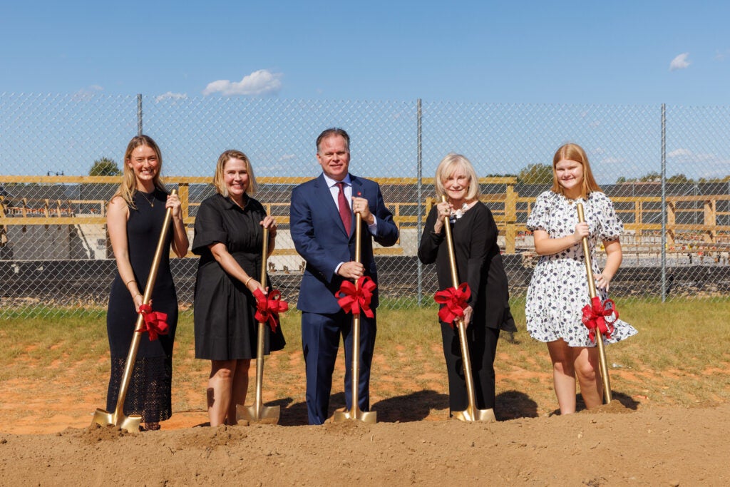 A family of five holds shovels at a groundbreaking ceremony.