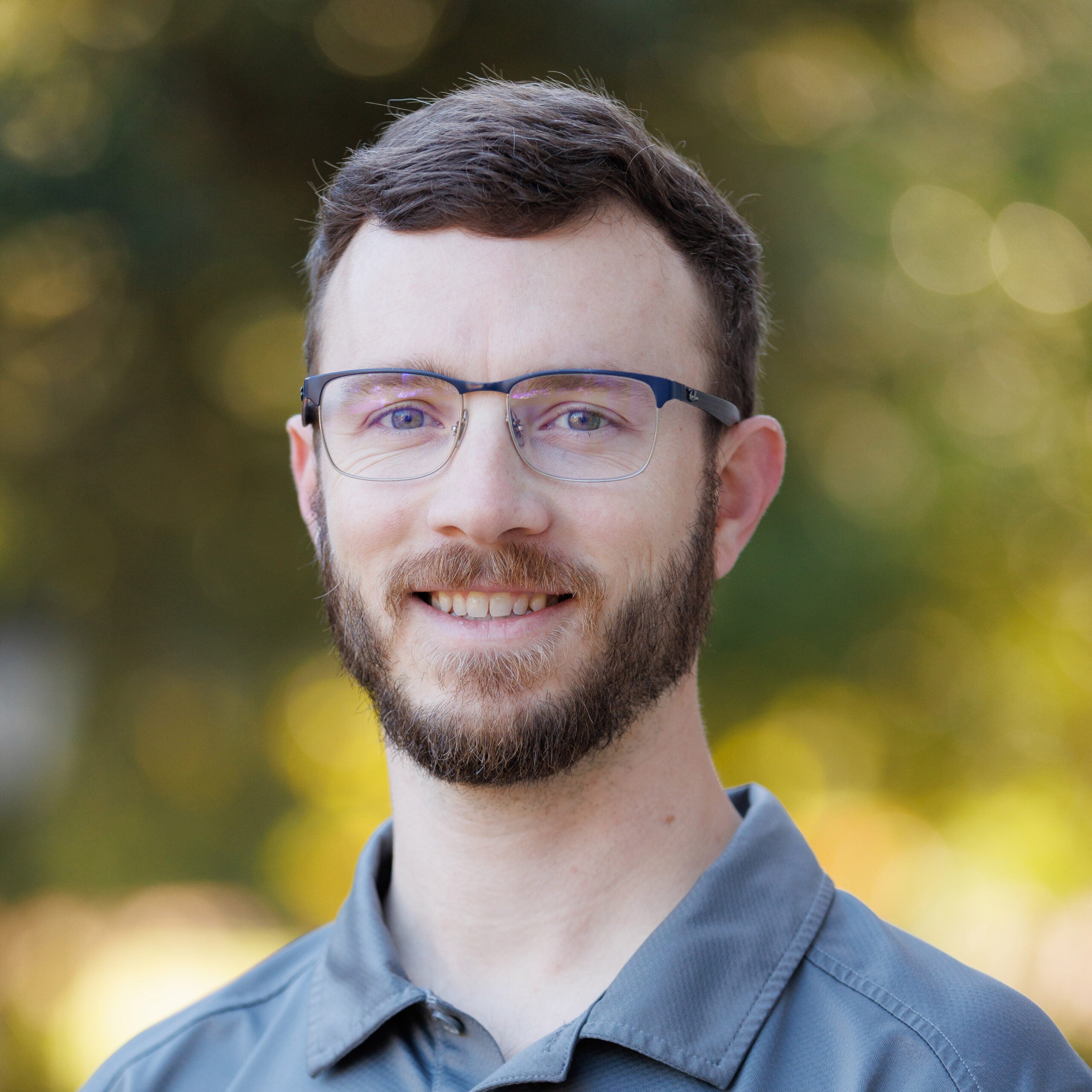 A white man poses for a photo outdoors