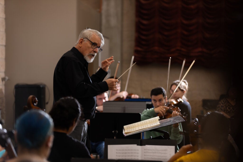 A white male conducts an orchestra