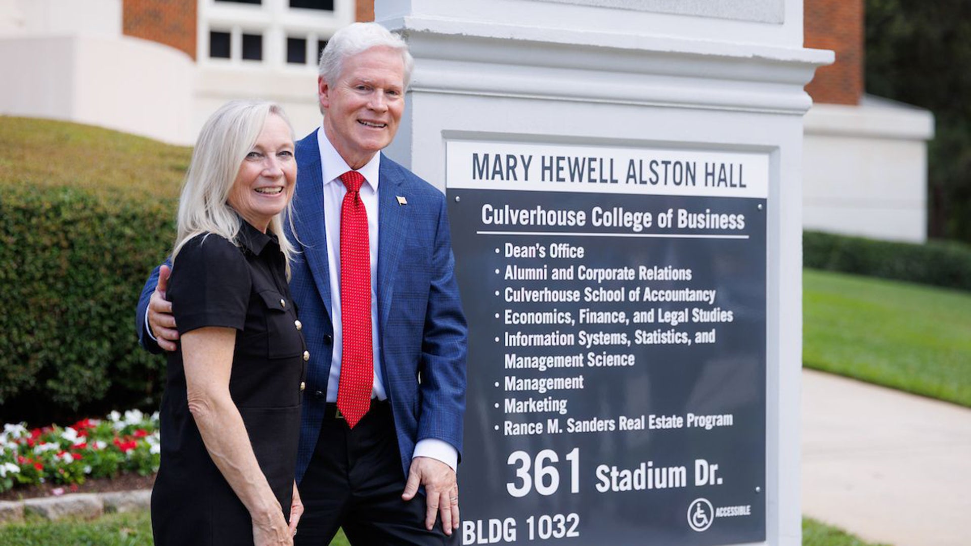 A man and a woman pose for a photo next to a sign.