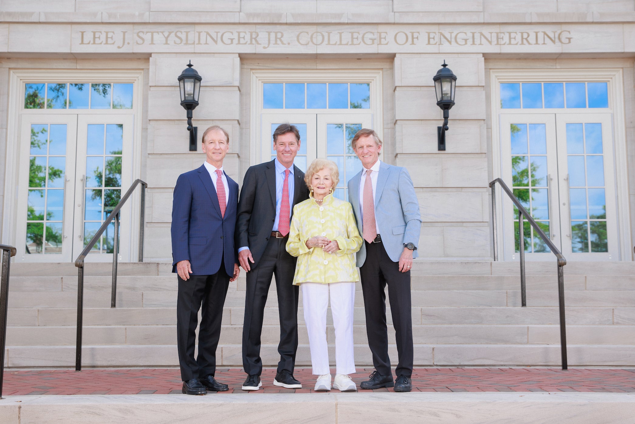 Three men and a woman pose for a photo in front of a building
