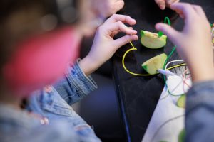 A young female student plugs robotics parts into apple slices